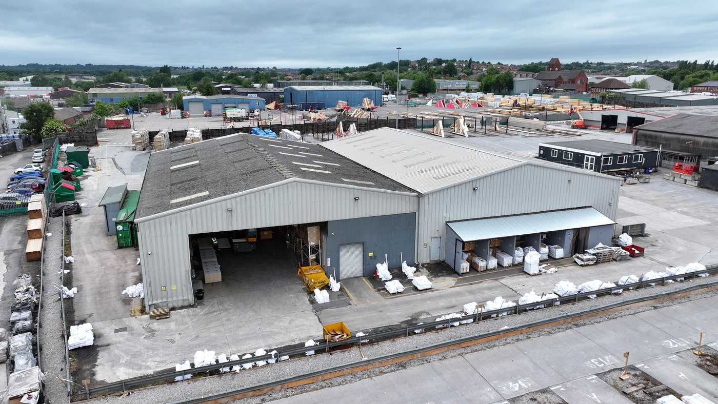 Aerial of a large-span logistics warehouse with parking apron assessed by Solar Surveys for steel-frame solar PV structural deployment at scale.