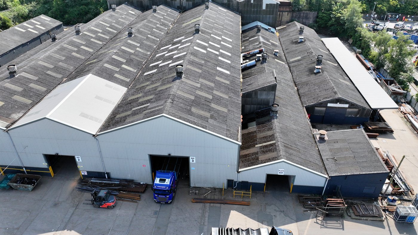 Aerial of a large-span industrial works roof -- representative of the building stock Solar Surveys inspects under its commercial roof inspection pricing guide.