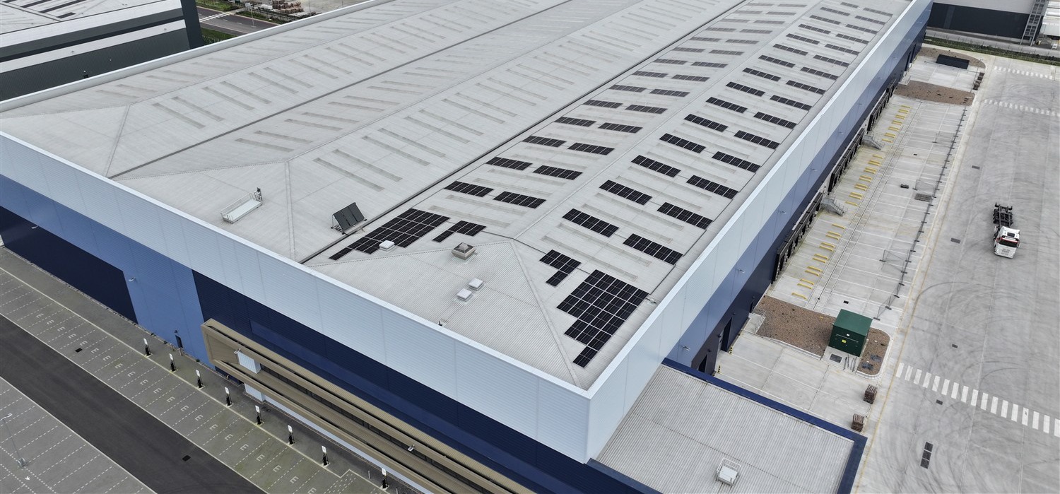 Aerial view of a large port logistics distribution warehouse roof carrying a rooftop solar PV array