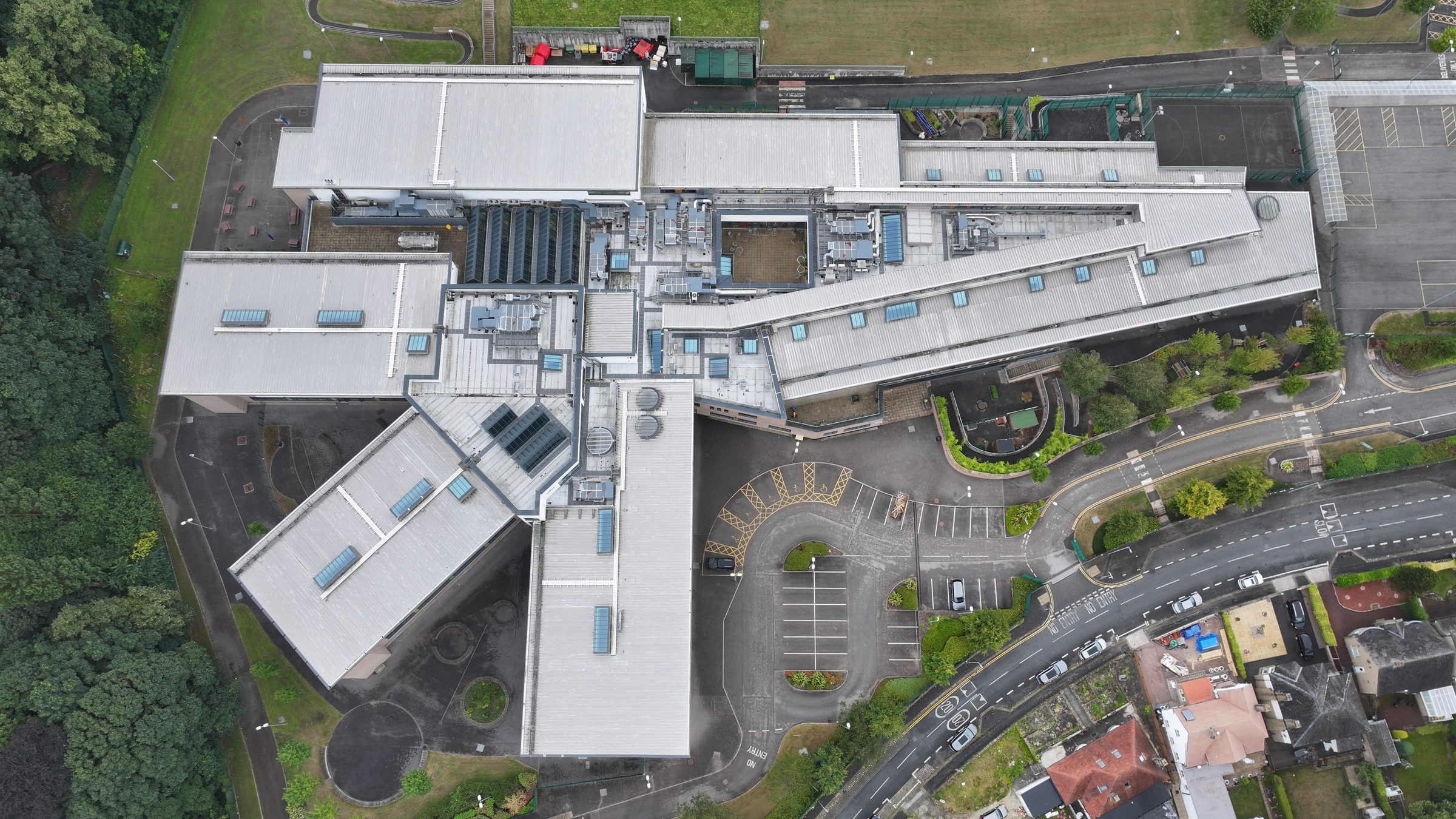 Top-down drone technical survey aerial of complex educational campus roof showing multiple roof levels, mixed substrate types, mono-pitch and flat membrane sections: hard-to-access geometry captured non-intrusively for structural inspection and condition assessment