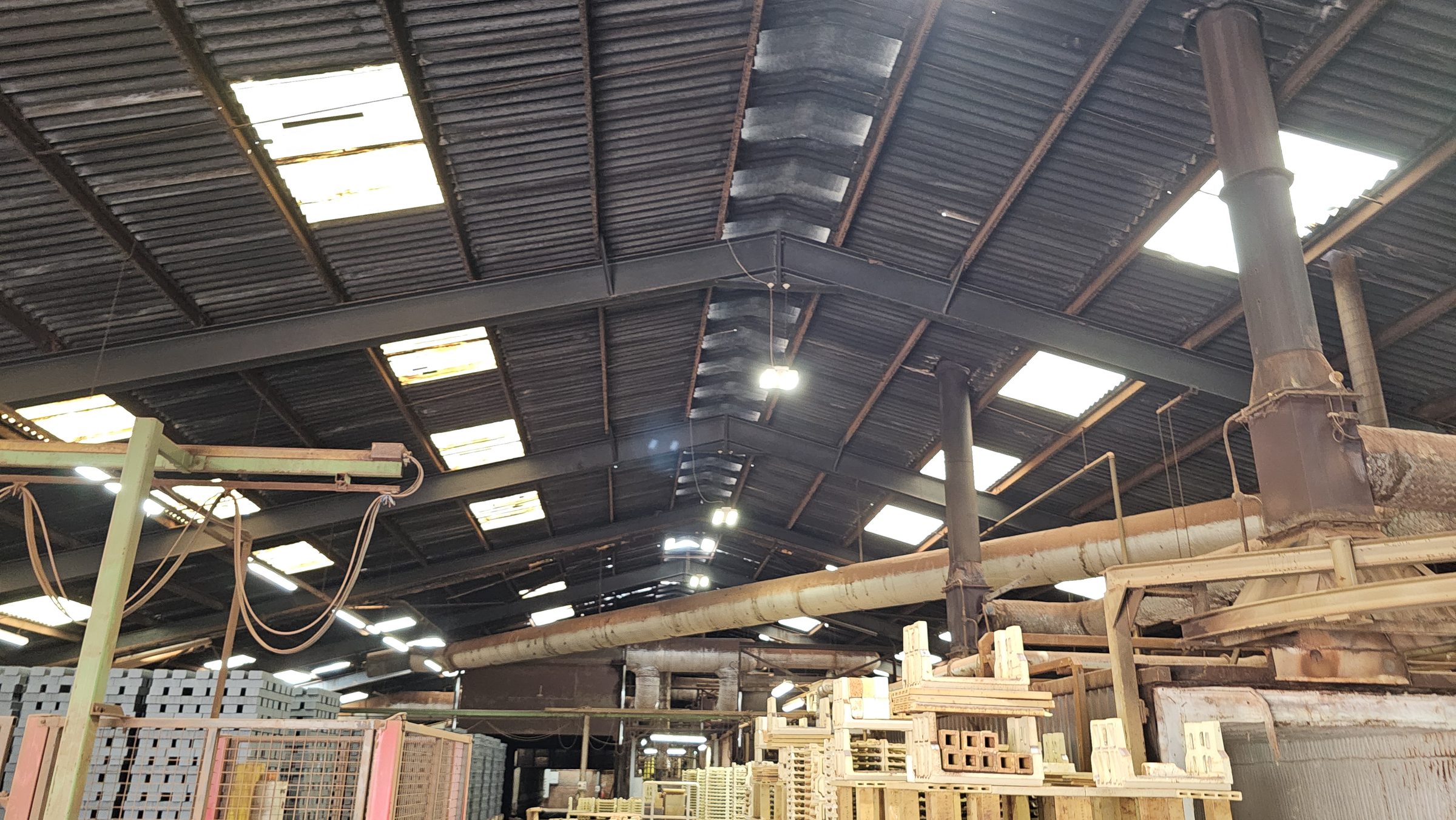 On-site structural survey: corrugated metal roof internal inspection showing rooflights, structural ridge and column support to portal frame