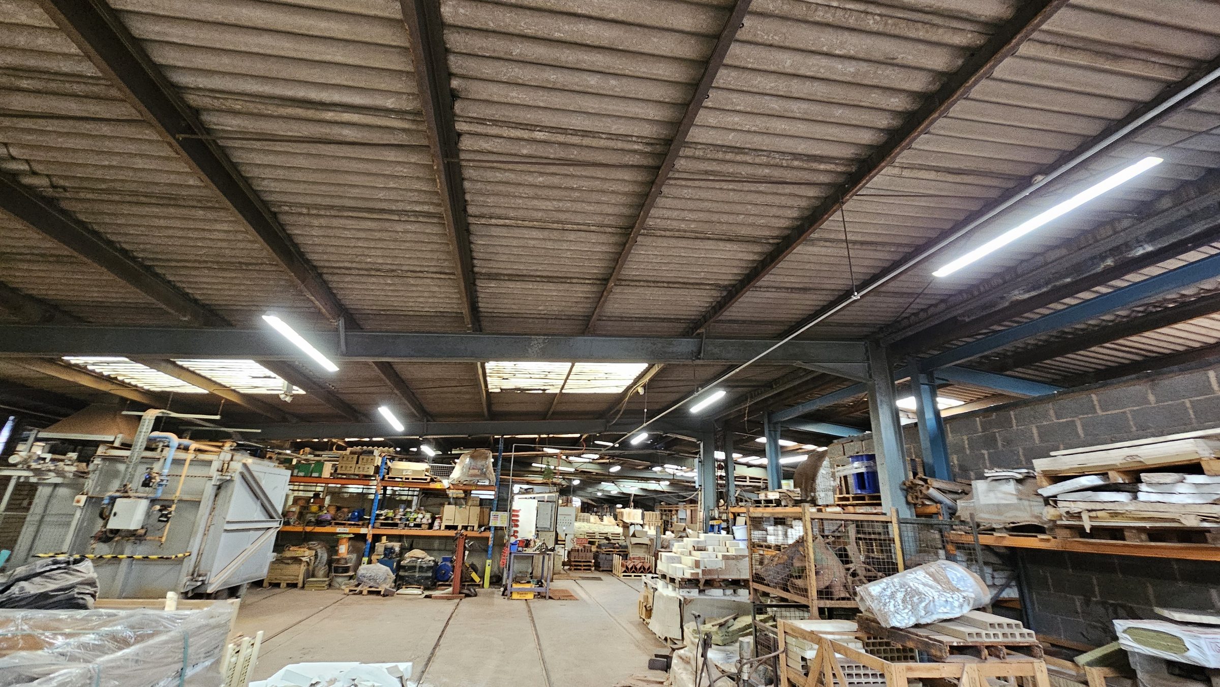 On-site structural survey: internal view of industrial portal frame steel structure showing column connections and roof bay rhythm